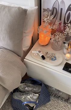 a white nightstand topped with lots of silver shoes next to a night stand filled with flowers