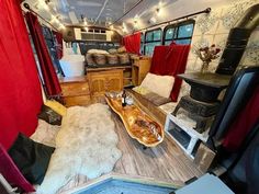 the interior of a camper with red curtains and wood flooring, including a couch