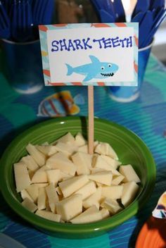 there is a green plate with toothpicks on it and a sign that says shark teeth