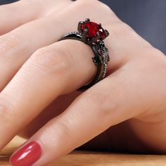 a woman's hand with a red manicured nail polish and ring on it