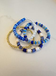 Blue and gold clay bead bracelet collection. Clay Bracelet Color Ideas, Navy Blue Clay Bead Bracelets, Cute Ideas For Clay Bead Bracelets, Fun Clay Bead Bracelet Ideas, Blue Heishi Beads Bracelet With Gold Beads, Blue Heishi Beads Bracelet With Gold Accents, Dark Blue Clay Bead Bracelet, Blue Beaded Bracelets With Gold Beads, Adjustable Blue Bracelets With Gold Beads