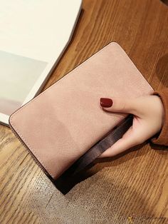 a woman's hand holding onto a pink purse on top of a wooden table