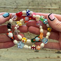 a person holding several bracelets made out of glass beads and other colorful items in their hands