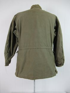 "Vintage 1940s WWII U.S. Army military M-1943 field jacket. Made of green cotton. Has chinstrap, button front, four pockets, shoulder epaulets and drawstring at the waist. Size 34R. Size small/medium. Actual measurements are: 42\" at the chest 40\" at the waist 18.5\" shoulder seam to shoulder seam 21\" shoulder seam to cuff 30\" overall length In wrecked condition. Has small spots of tar, paint, some cracked and replaced buttons. Wear hole at collar." Combat Style Khaki Cotton Utility Jacket, Khaki Cotton Combat Utility Jacket, Vintage Olive Utility Jacket For Fall, Vintage Khaki Parka For Fall, Vintage Khaki Utility Jacket For Winter, Vintage Khaki Utility Jacket For Outdoor, Vintage Khaki Utility Jacket With Flap Pockets, Vintage Long Sleeve Utility Jacket, Vintage Khaki Parka For Outdoor