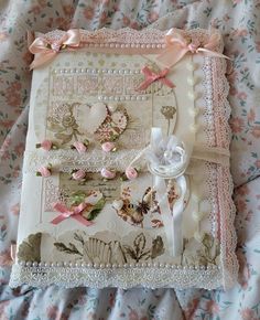 a close up of a greeting card on a bed with pink flowers and ribbons around it