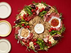 a platter with meats, cheeses and vegetables on it next to two plates