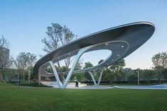 an artistically designed sculpture in the middle of a grassy area with trees and bushes