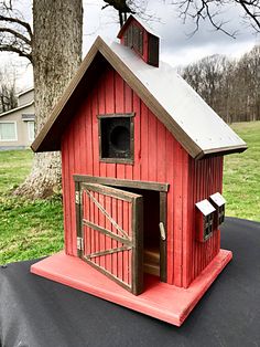 a small red barn with a door and window on top of a trampoline