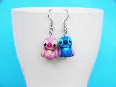 two little blue and pink birds sitting on top of a white cup next to each other