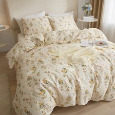 a white bed with yellow flowers on it in a room next to a lamp and window