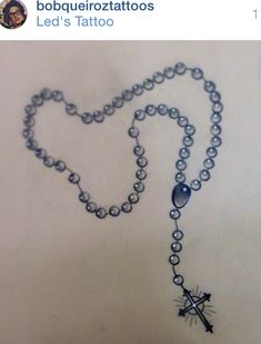 a rosary with a cross and an arrow on it is shown in black ink, as well as the caption bobauelitozzitatos led's tattoo