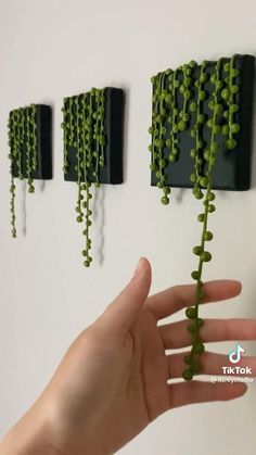 a hand is holding some green beads on the wall