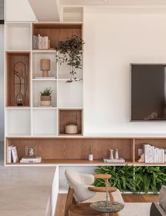 a living room filled with furniture and a flat screen tv mounted on a wall above a wooden shelf