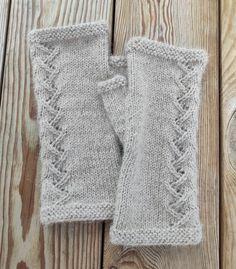 two gray knitted mittens sitting on top of a wooden floor next to each other