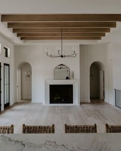 an empty living room with fireplace and chandelier in the center, surrounded by white marble