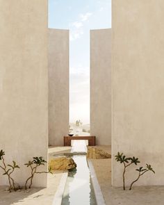 an empty walkway between two white walls with water running through it and trees in the distance