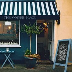 the coffee place is located in front of a building with an awning over it