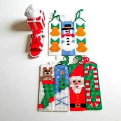 cross stitch christmas tags with santa, snowman, and other items hanging from them