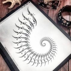 an artistically designed artwork is displayed on a wooden table next to some bracelets