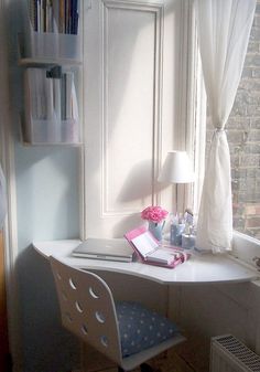 a desk with a laptop computer on top of it in front of a window next to a book shelf