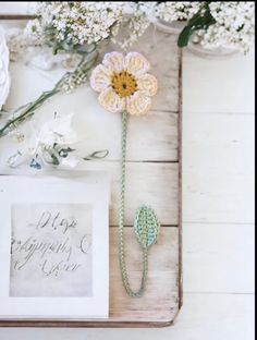 a white flower sitting on top of a wooden table next to a card and flowers