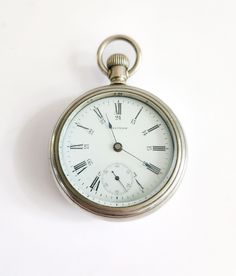 an old silver pocket watch with roman numerals