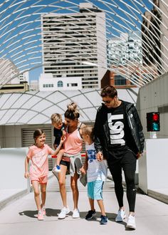 a group of people walking down a street next to each other with buildings in the background