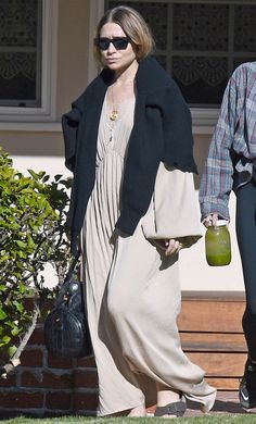 the woman is walking down the sidewalk with her hand in her purse and another person wearing sunglasses