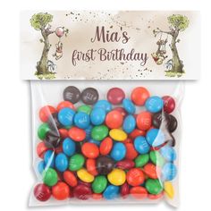 a bag filled with lots of colorful candies next to a sign that says cheers first birthday