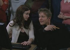 a young man and woman sitting at a desk with a keyboard in front of them