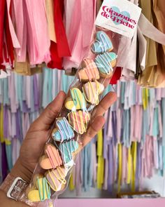 a person holding up a bag of cookies in front of colorful ribbons and paper streamers