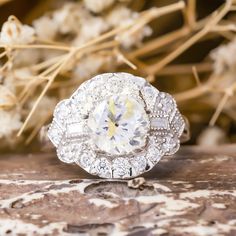 a diamond ring sitting on top of a wooden table next to dried flowers and branches