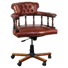 a brown leather office chair sitting on top of a wooden desk with casteor wheels