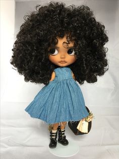 a doll with black hair wearing a blue dress and holding a purse in her hand