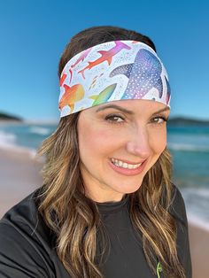 a woman standing on the beach wearing a headband with colorful fish and seagulls