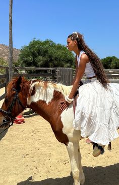 a woman riding on the back of a brown and white horse