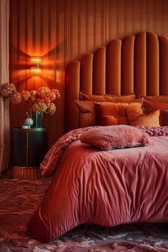 a bed with pink sheets and pillows in a bedroom next to a lamp on a table