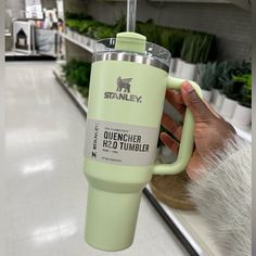 a person holding up a green cup in a store