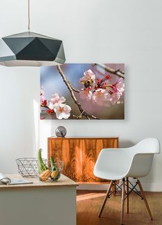 a white chair sitting in front of a table next to a painting on the wall