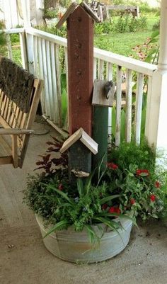 a bird house sitting on top of a planter next to a wooden bench and rocking chair