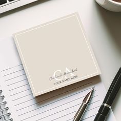 a notepad and pen sitting on top of a desk next to a cup of coffee