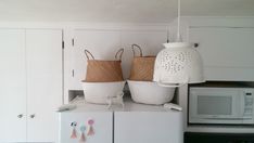 two baskets are sitting on top of a refrigerator in a kitchen with white cupboards