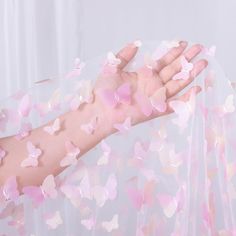 a woman's arm with pink butterflies on it, covering her hand and the background is white