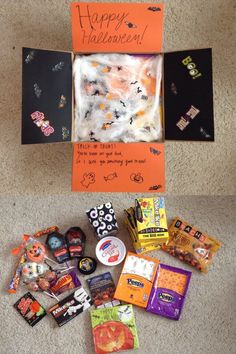 two boxes with candy and halloween decorations on the floor next to an orange sign that says happy halloween