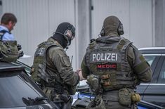 two police officers standing next to each other in front of some parked cars and talking