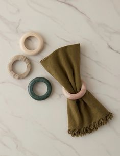 an assortment of rings and scarves laid out on a marble counter top with green scarf