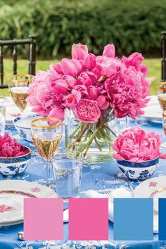 the table is set with pink flowers and blue dishes