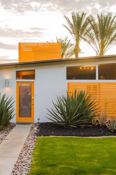 a house with yellow shutters and plants in the front yard