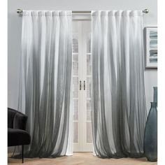 an open door with sheer curtains hanging on the side and a black chair in front