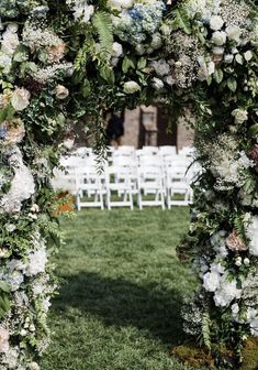 an outdoor wedding ceremony with white chairs and flowers on the arch over looking the grass